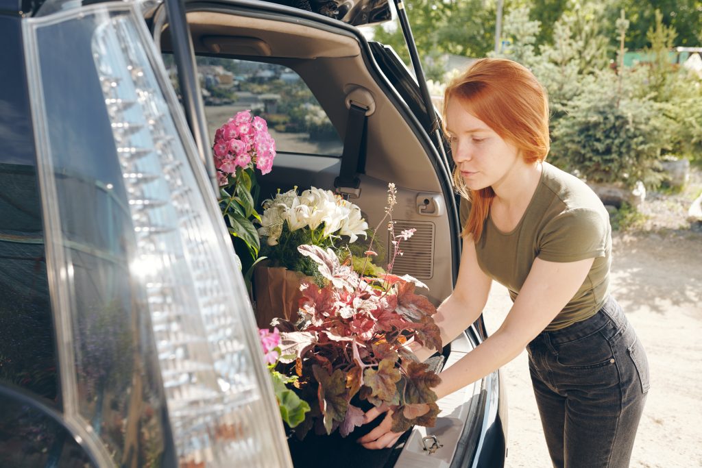 Kukkakauppias asettelee kukkia auton tavaratilaan